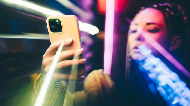 Woman using mobile phone in neon lights.